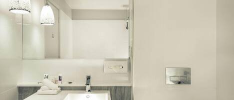 Un baño moderno con un espejo grande, un lavabo blanco y dos lámparas colgantes.
