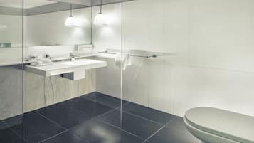 Un baño moderno con cabina de ducha de vidrio, un lavamanos blanco y un inodoro.