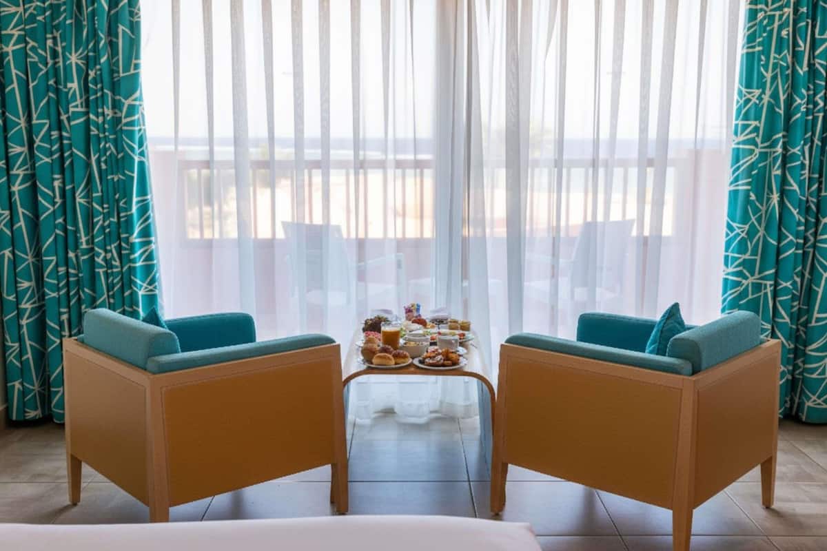 Una stanza con due divani, un tavolino con cibo e vista su un balcone.