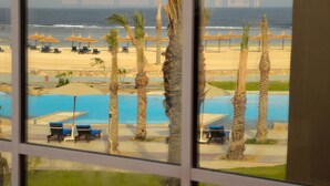 A view of a beach resort with a pool, palm trees, and beach umbrellas. - Novotel Marsa Alam Beach Resort (El Quseir)