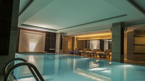 Ein Innenpool mit glatter Wasseroberfläche, einer Poolleiter und Liegestühlen entlang der Wand.