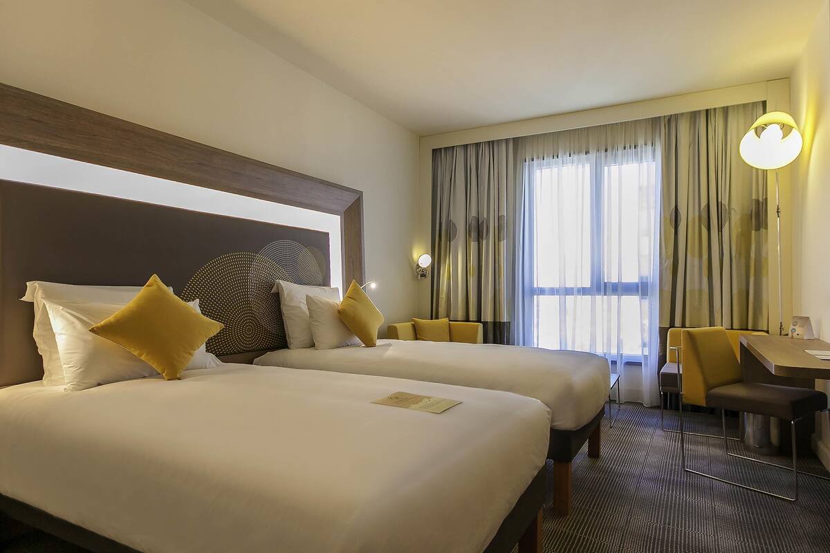 Ein Hotelzimmer mit zwei Betten, einem Schreibtisch und einem Sessel.