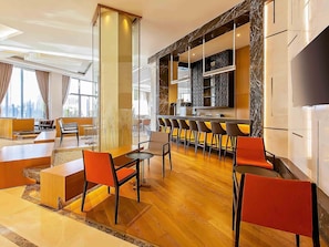 Een moderne hotellobby met een bar, zitplaatsen en uitzicht op de stad.