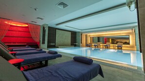 Ein moderner Poolbereich im Innenbereich mit Liegestühlen und einer Rezeption.