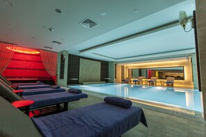 Een modern zwembad met loungebedden en een receptiebalie.