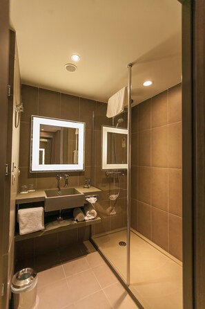 Een moderne badkamer met een grote spiegel, een wastafel en een douche.