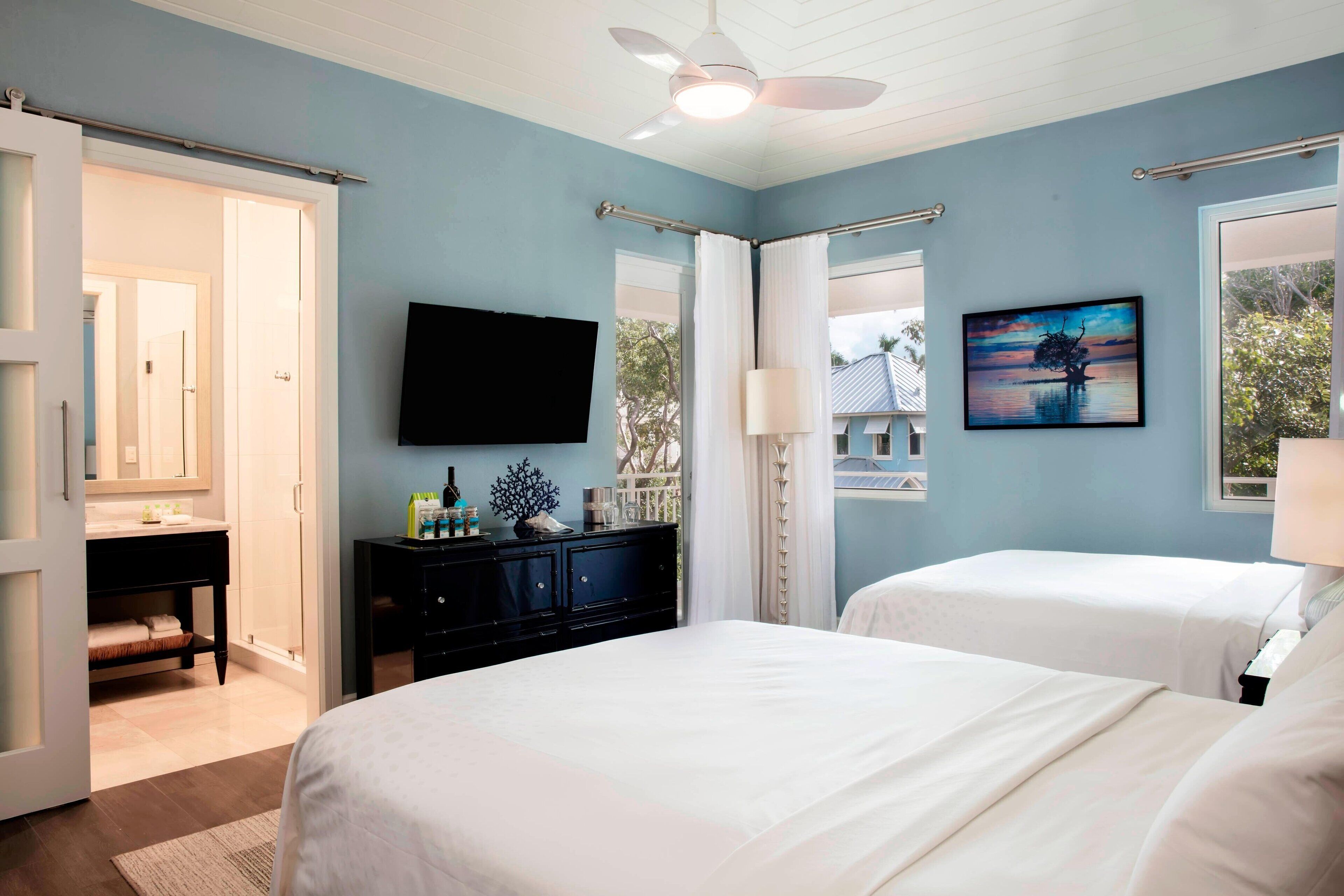 A bedroom with two beds, a TV, and a painting.