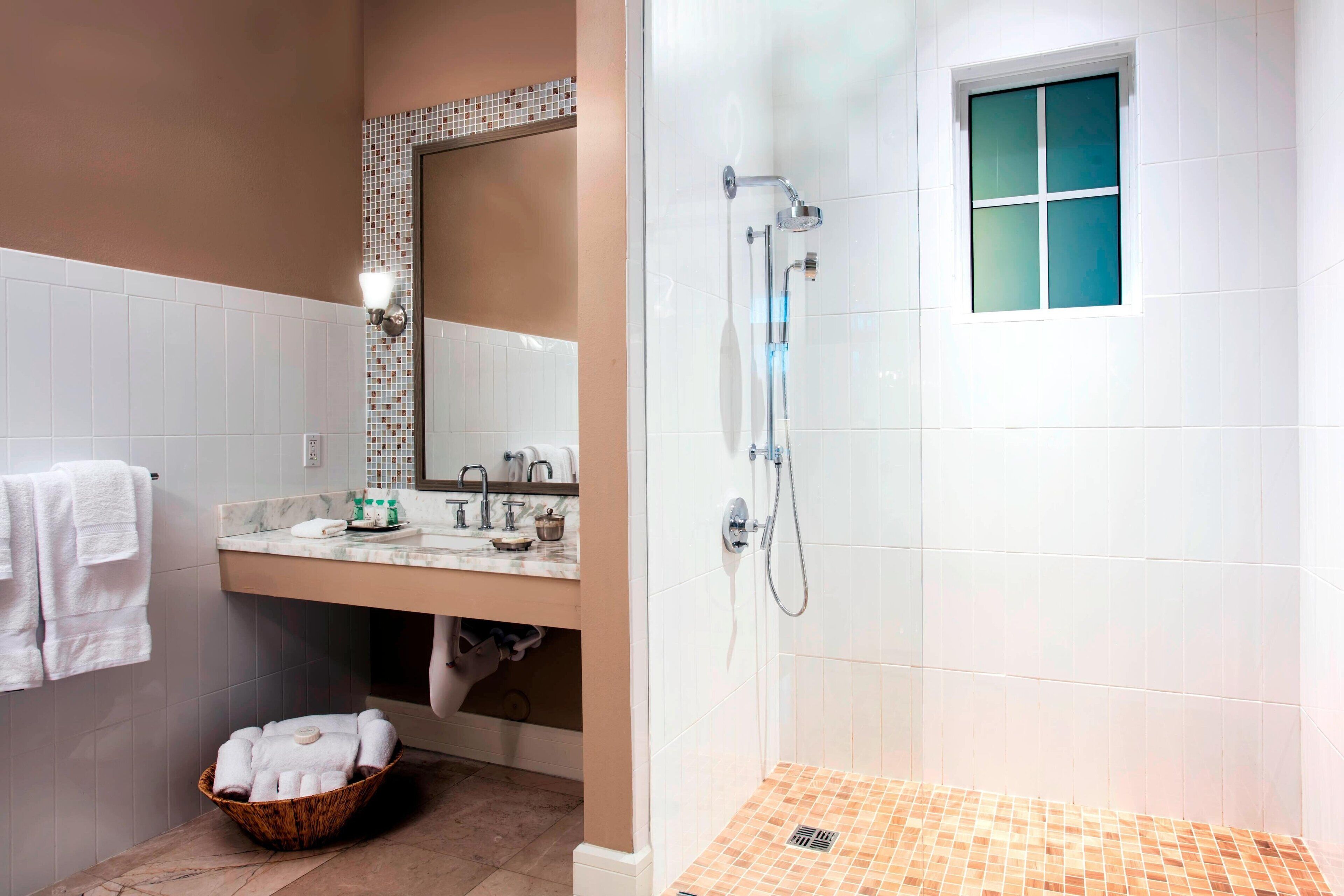 A bathroom with a shower, sink, and a mirror.