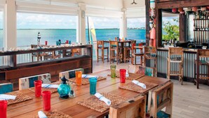 A restaurant with wooden tables and chairs, a bar area, and a view of the sea. - Playa Largo Resort & Spa, Autograph Collection (Key Largo)