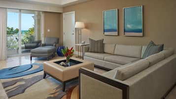 A living room with a sofa, armchair, and ottoman, a vase with flowers, and two framed artworks on the wall.