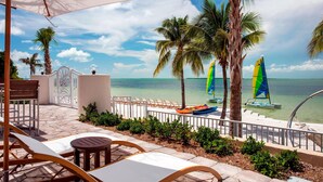 A beachside patio with lounge chairs, a table, and a view of the ocean. - Playa Largo Resort & Spa, Autograph Collection (Key Largo)