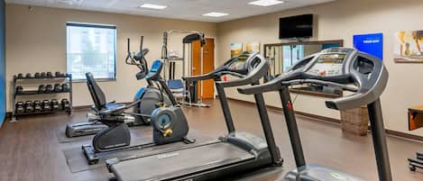 Un gimnasio con cintas de correr, elípticas y pesas sueltas.