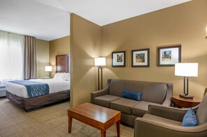 A hotel room with a bed, a sofa, a coffee table, and a desk with a lamp. There are framed pictures on the wall. - Comfort Inn & Suites Lynchburg Airport - University Area (Lynchburg)