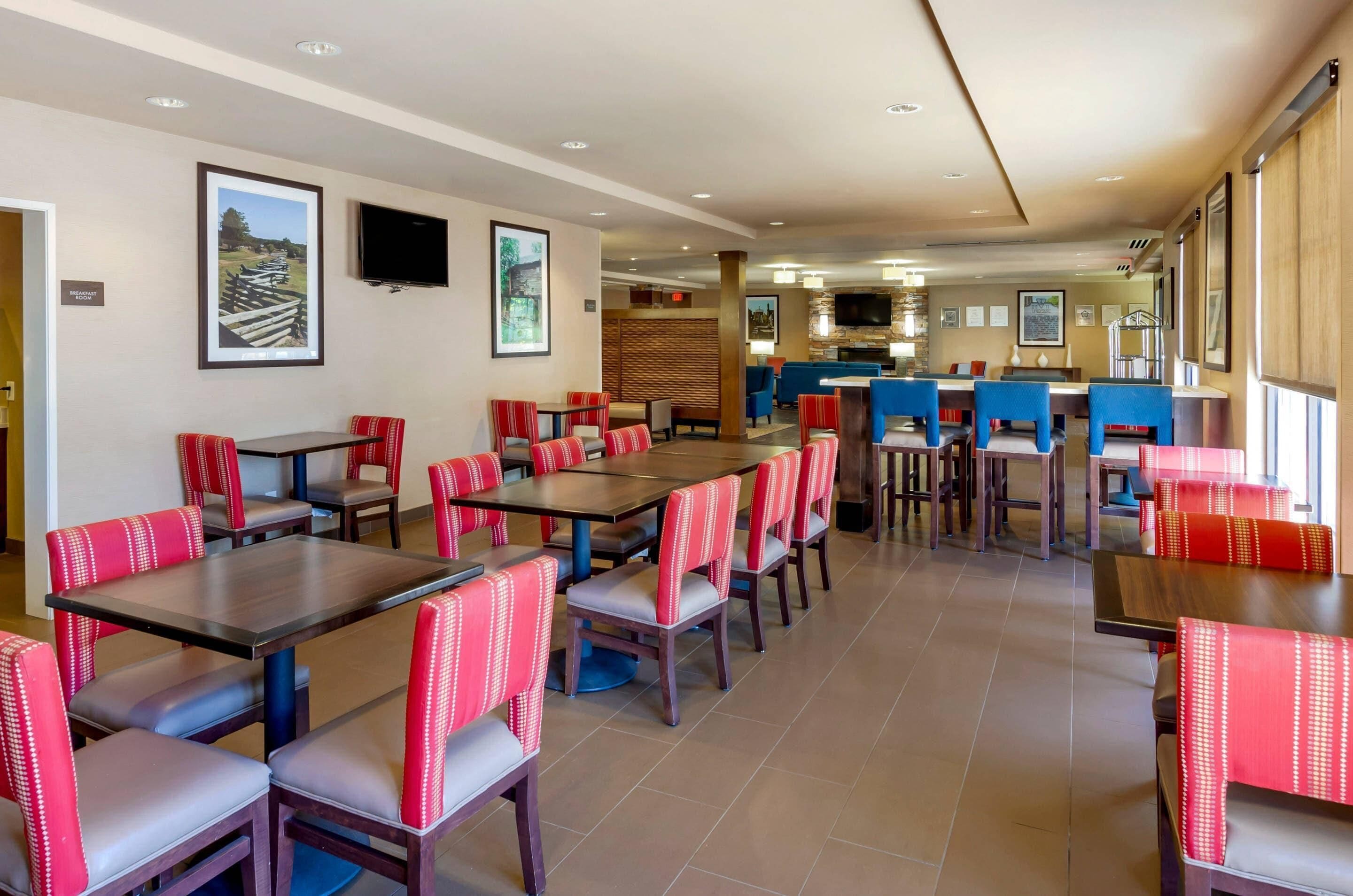 A restaurant with multiple tables and chairs, a television mounted on the wall, and framed pictures on the walls.