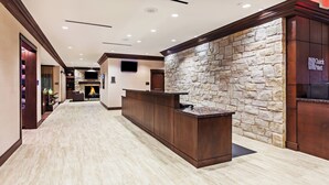 A reception area with a stone wall, a wooden reception desk, and a fireplace in the background.