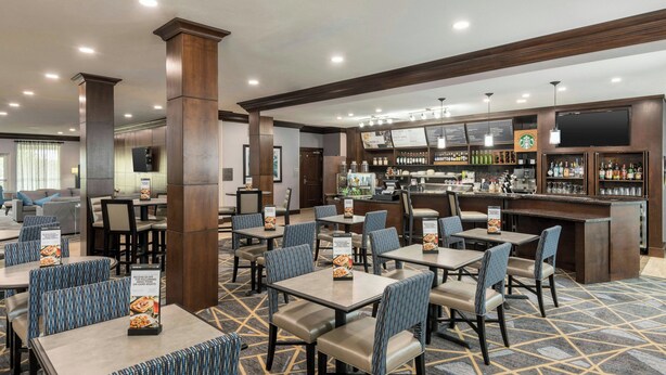A hotel lobby with multiple seating areas, a bar, and a coffee station.