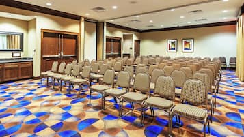 A conference room with rows of chairs, a wooden counter, and a patterned carpet.