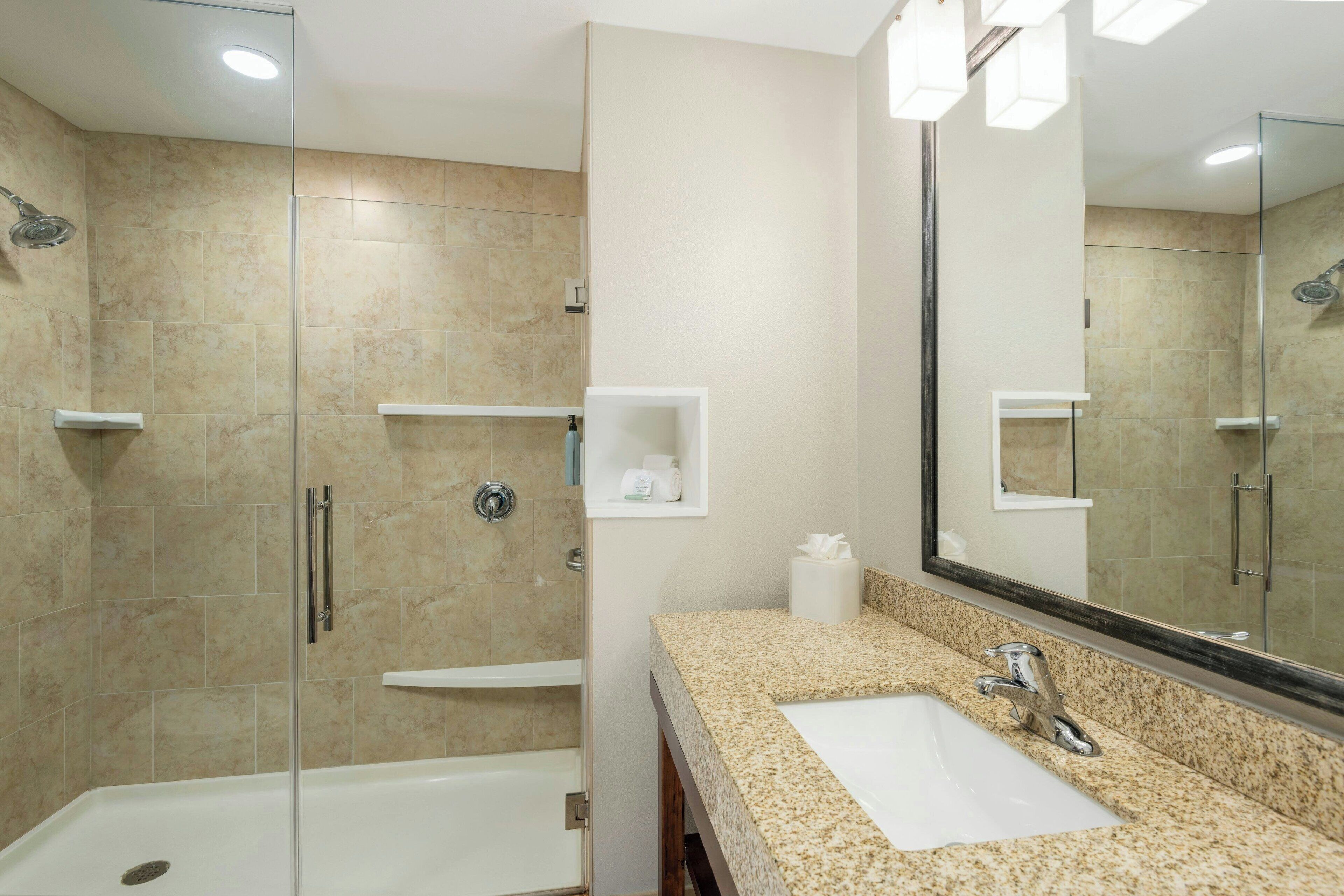 Une salle de bain moderne avec une douche à parois de verre, un lavabo blanc et un grand miroir.