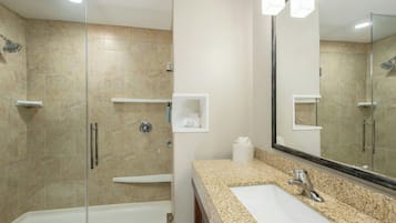 Une salle de bain moderne avec une douche à parois de verre, un lavabo blanc et un grand miroir.