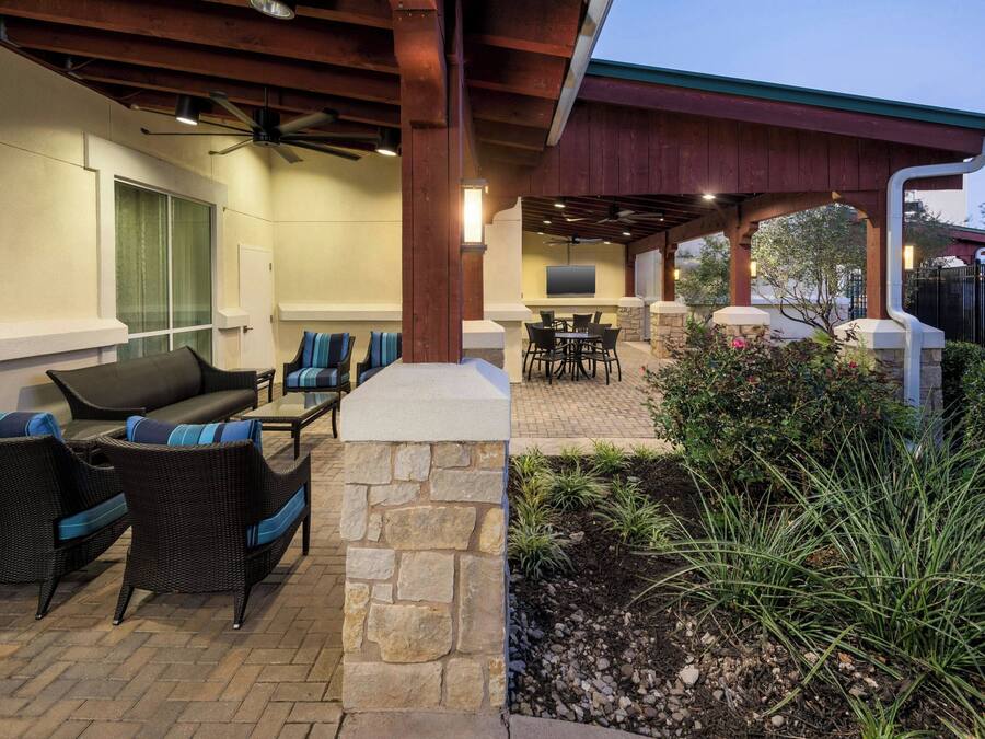 An outdoor patio with wicker furniture, a stone column, and a grill area.