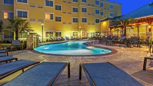 A hotel pool area with lounge chairs, a swimming pool, and a building with multiple balconies.