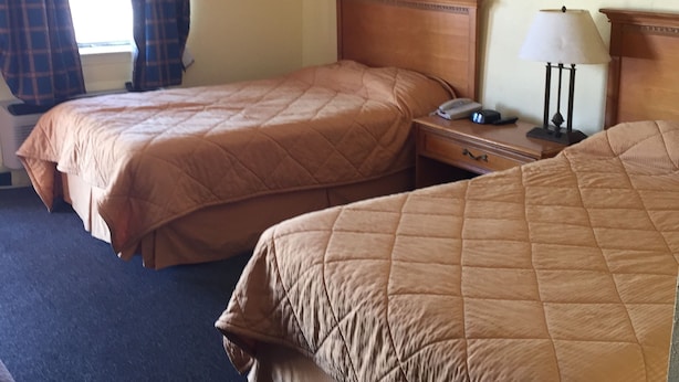 Ein Hotelzimmer mit zwei Betten, einem Nachttisch, einer Lampe und einem Bild an der Wand.