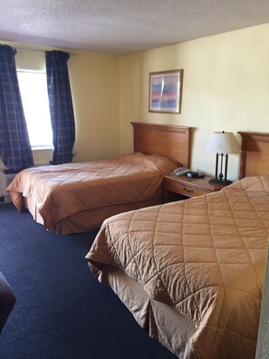 A hotel room with two beds, a nightstand, a lamp, and a painting on the wall. - Park Hill Inn and Suites (Oklahoma City)