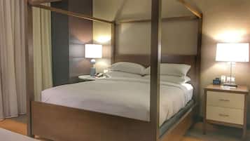 Un lit à baldaquin avec un cadre en bois, deux tables de chevet avec des lampes et une petite commode.