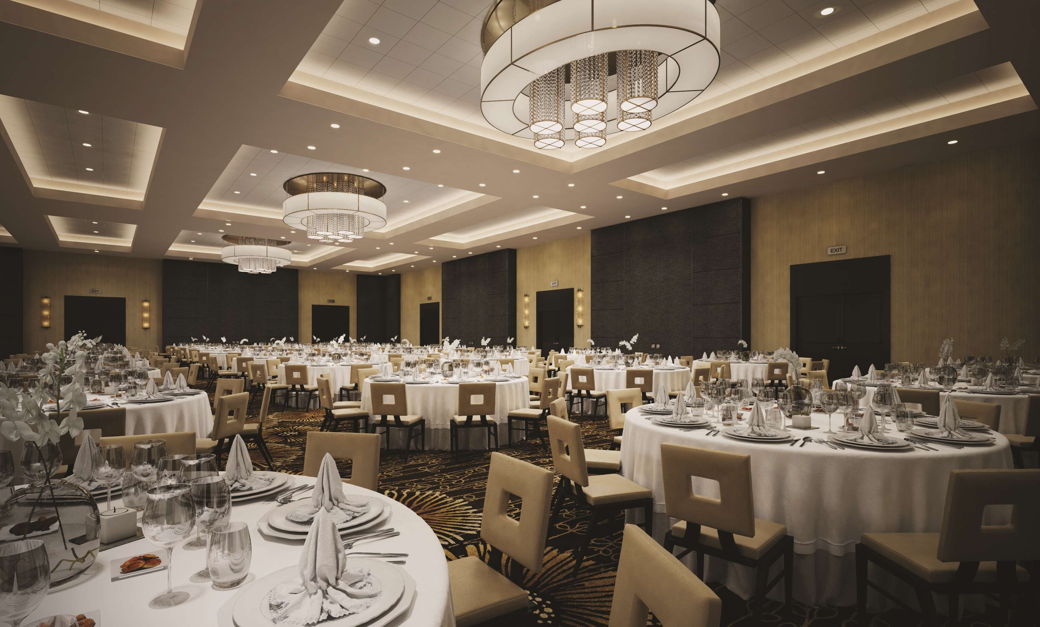 A large banquet hall with round tables set for dining, featuring chandeliers and wall sconces.