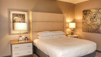 A hotel room with a large bed, a nightstand with drawers, a framed picture, and a wall art piece.