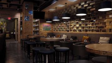 A cozy bar area with wooden shelves, hanging lights, and stools.
