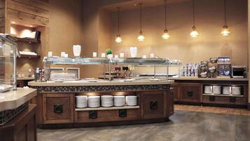 A buffet area with a central serving station, multiple food display cases, and a variety of food items.