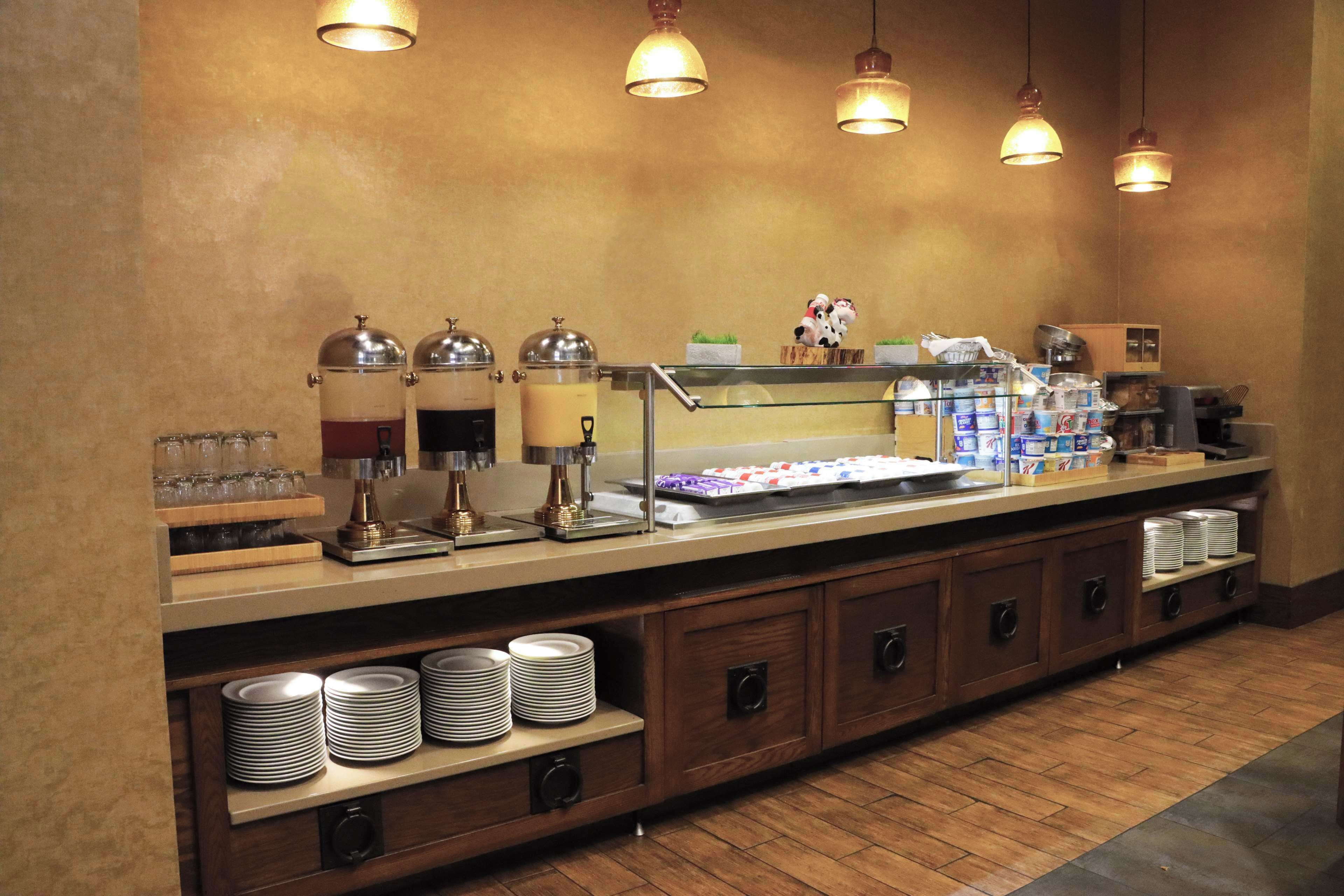 A buffet setup with various food items, a coffee station, and a glass display case.