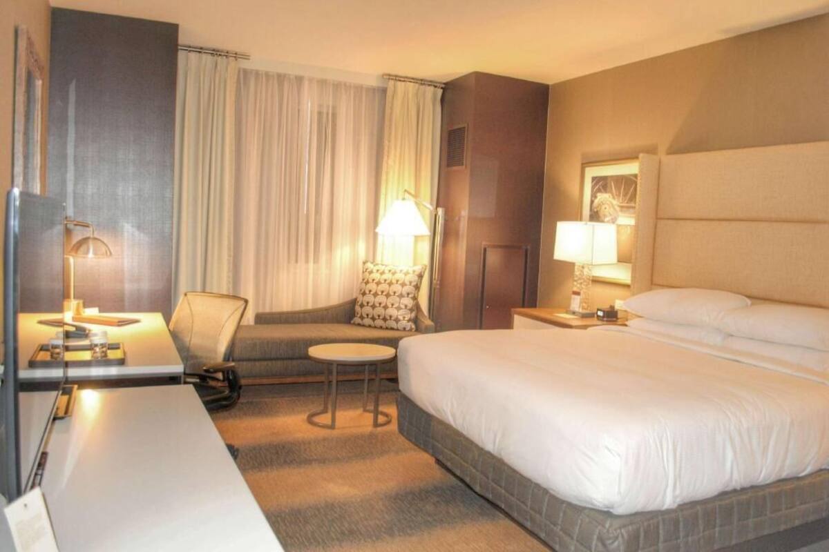 A hotel room with a bed, a desk, a chair, and a small table.