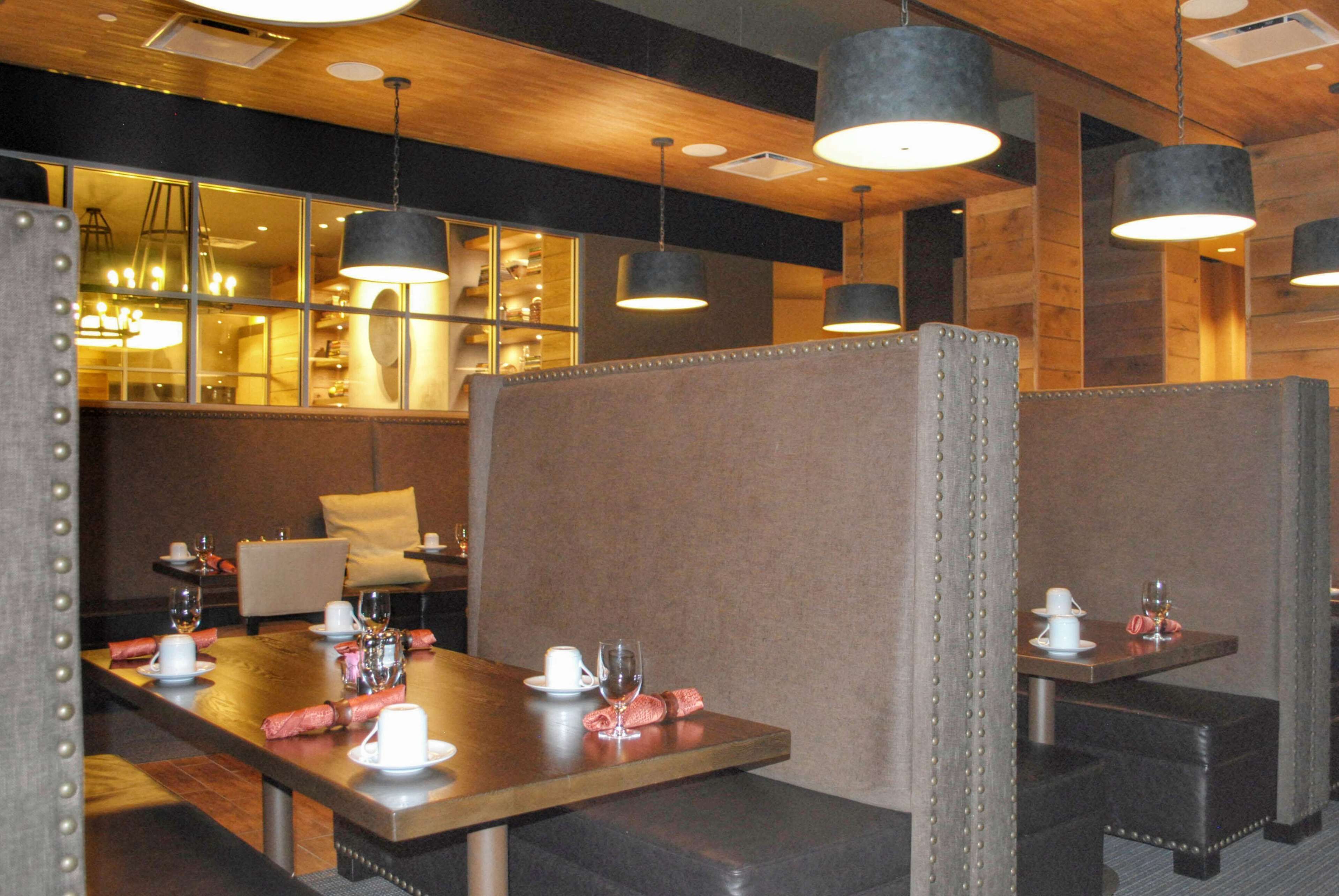 Un restaurant avec des banquettes, des tables et des lampes suspendues.