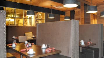 Un restaurant avec des banquettes, des tables et des lampes suspendues.
