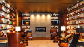 A cozy, well-lit living room with leather armchairs, a fireplace, and bookshelves filled with books and decorative items. - Doubletree By Hilton Reading (Reading)