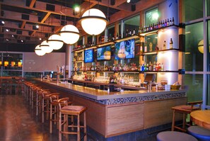 A bar area with multiple seating options, a well-stocked bar counter, and several televisions mounted on the wall. - Doubletree By Hilton Reading (Reading)