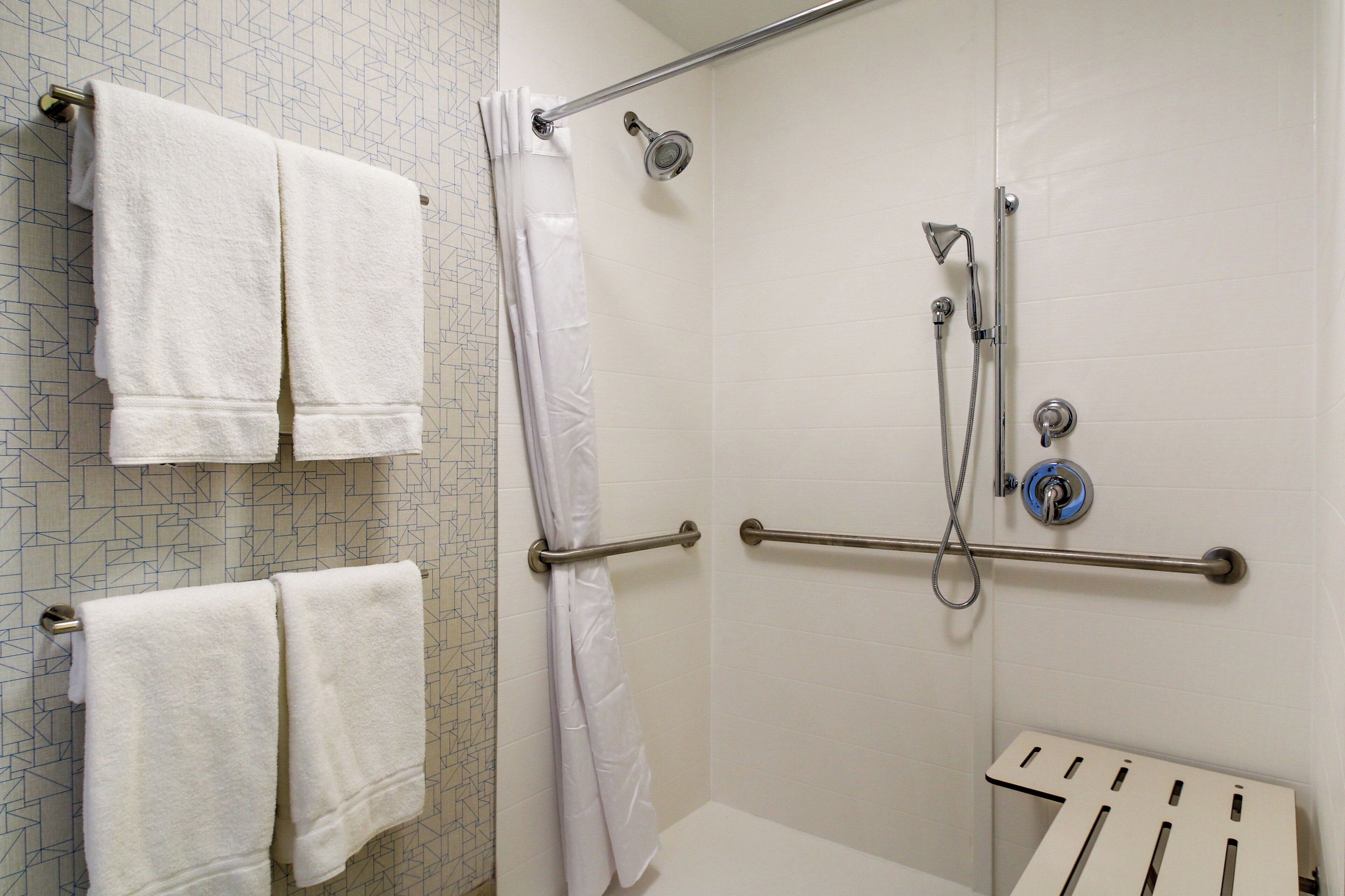 Een badkamer met een douche, grepen en een handdoekhouder.