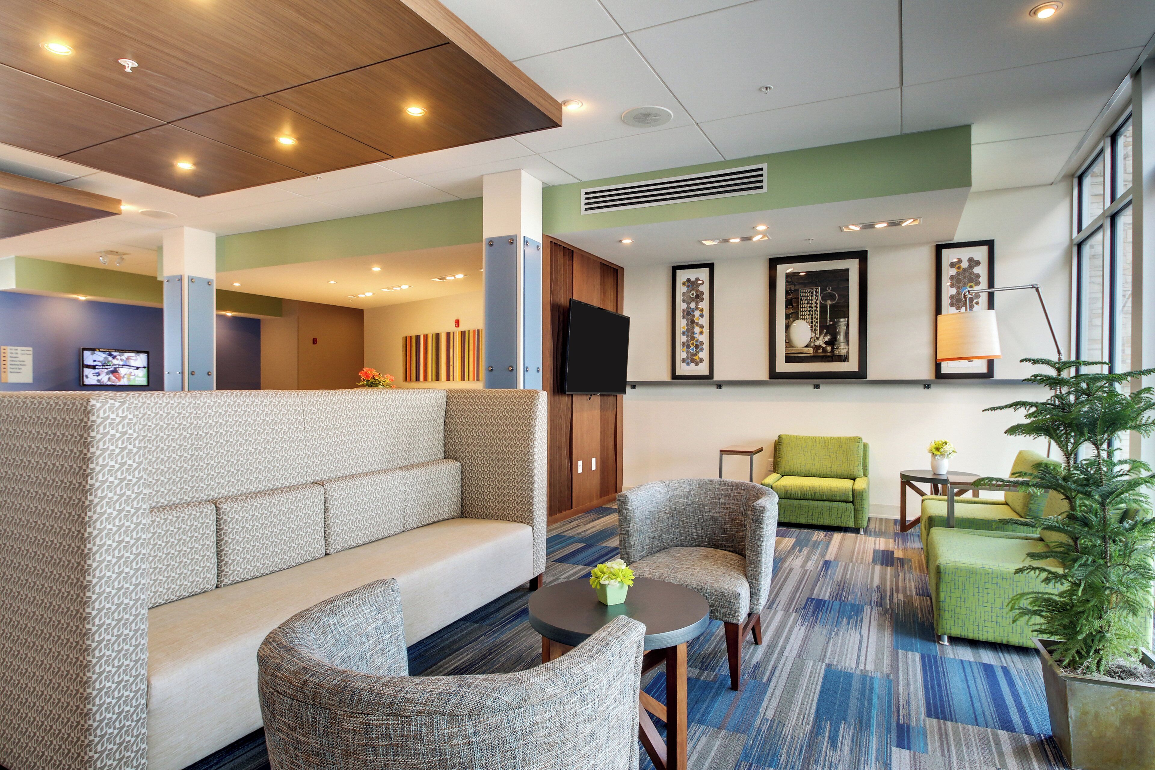 A hotel lobby with a seating area, a television, artwork on the walls, and a large window.