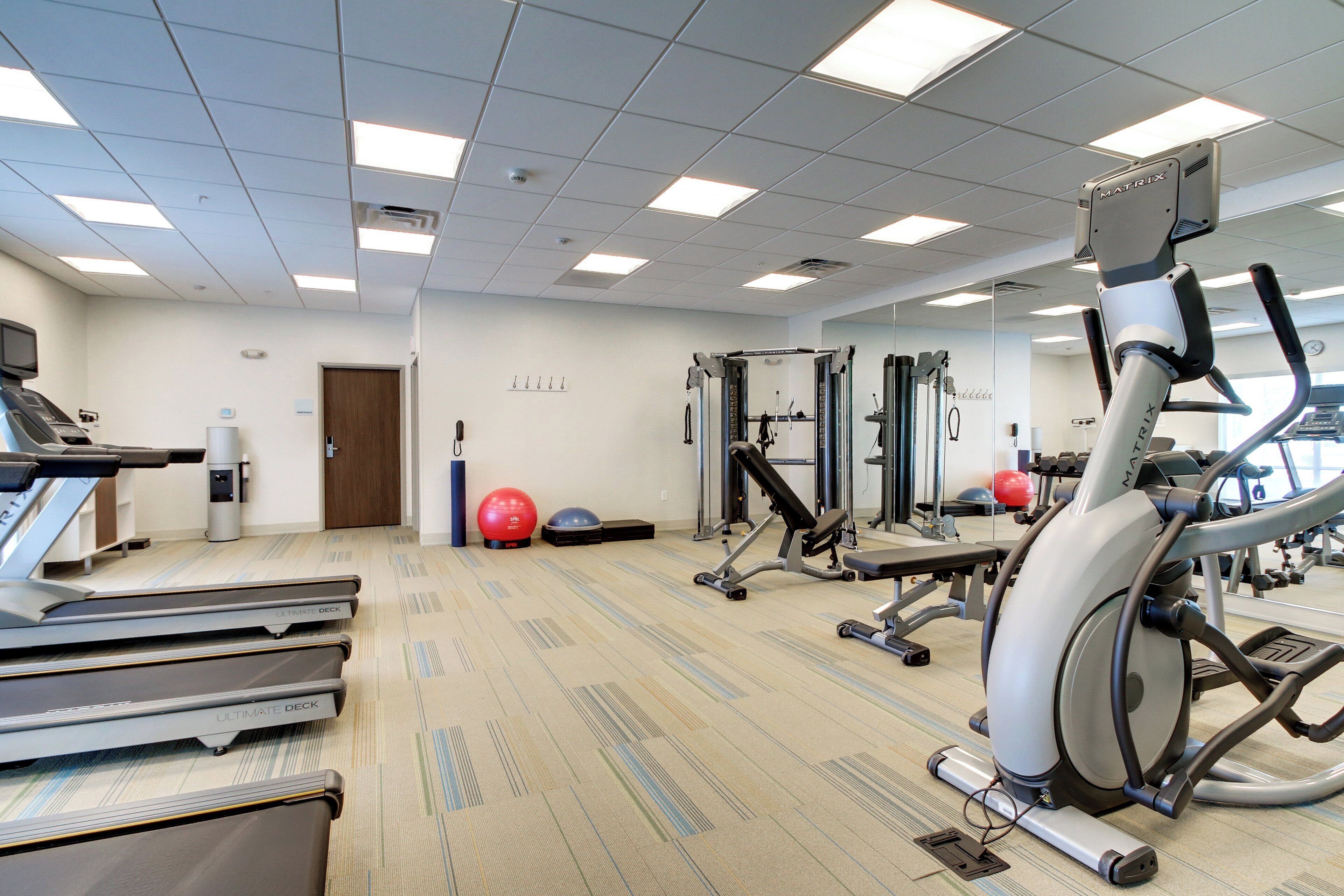 Ein Fitnessstudio mit Laufbändern, Crosstrainern, Kurzhanteln und Gymbällen.