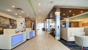A hotel reception area with a reception desk, seating area, and a view of the lobby.