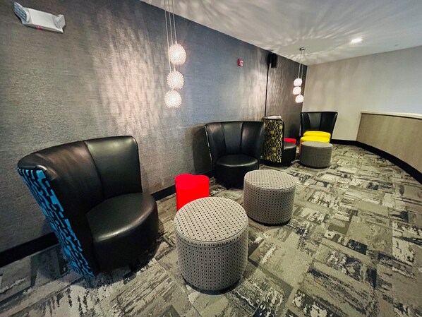 Un hall d’hôtel doté de sièges en cuir, de poufs et d’un tapis à motifs.