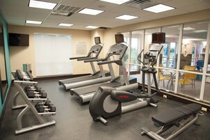 Un gimnasio con cintas de correr, elípticas y bancos de pesas.