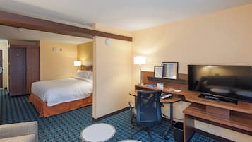 A hotel room with a bed, desk, chair, TV, and a small table.