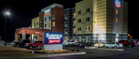 Un hotel Fairfield Inn & Suites by Marriott de noche con varios coches estacionados en el estacionamiento.