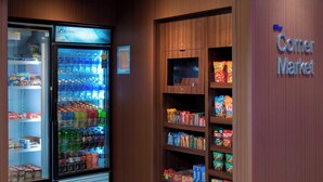 Une petite épicerie de quartier avec un présentoir réfrigéré pour les boissons et des étagères remplies d’en-cas et de produits alimentaires.