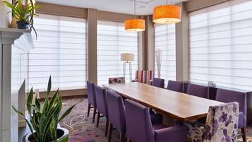 A conference room with a long table, purple chairs, and two orange pendant lights.