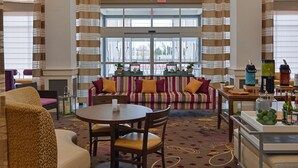 A hotel lobby with a central seating area, a coffee station, and large windows. - Hilton Garden Inn Hobbs (Hobbs)