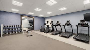 Un gimnasio con cintas de correr, elípticas y mancuernas.